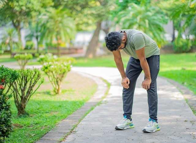 Tired young man runner taking a rest after running hard at the park