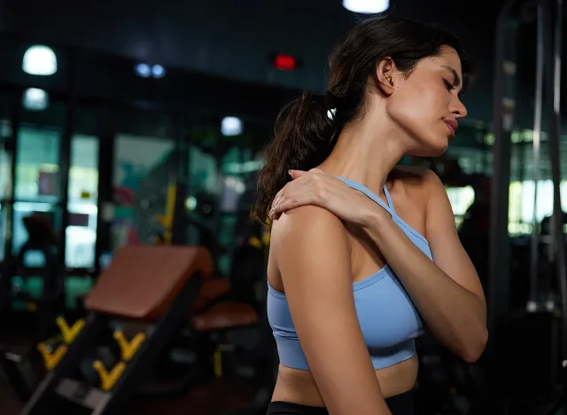 young sporty woman shoulder pain from workout in the gym