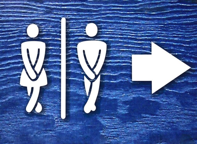 public toilet sign board with white woman and man figure and arrow on blue background or surface with noise effects. public toilet or wc sign board photo with selective focus and copy space on blue