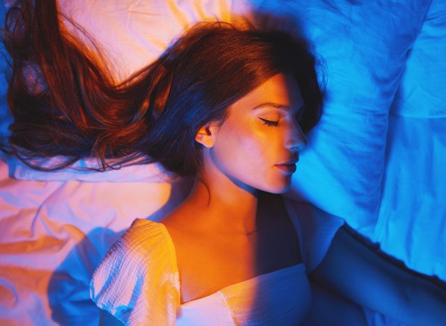 Sleeping beauty, lights and woman with sleep and creative neon lighting. Resting, face and model glow and feeling relax and calm on a bed pillow with aesthetic profile in a bedroom bed at home