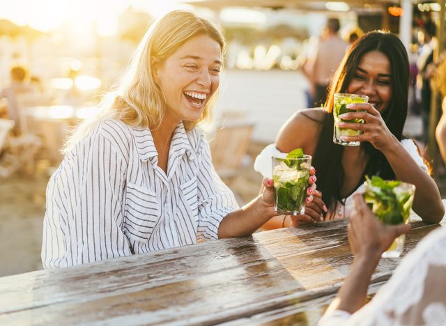 Happy girls having fun drinking cocktails at bar on the beach - Soft focus on left girl face