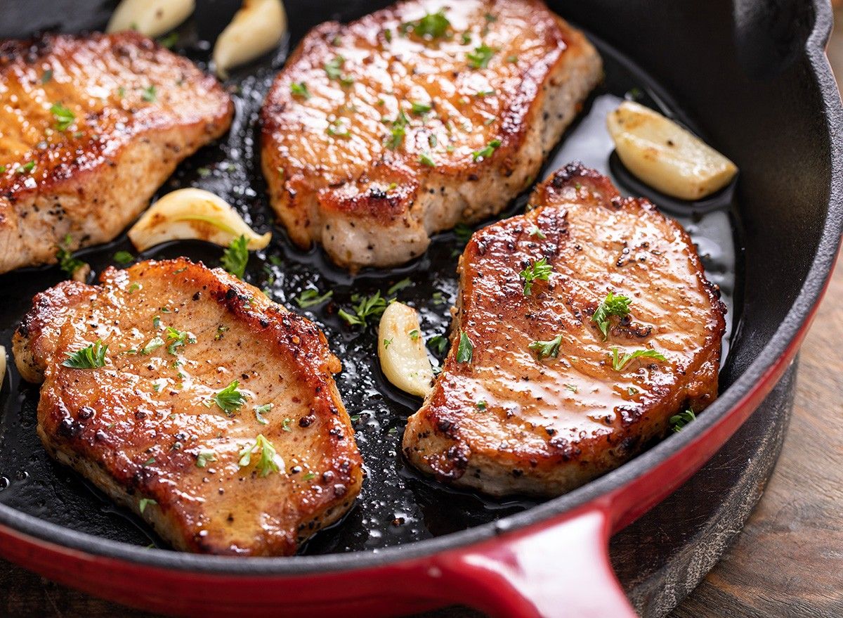 Pork chops cooked with garlic in a cast iron pan