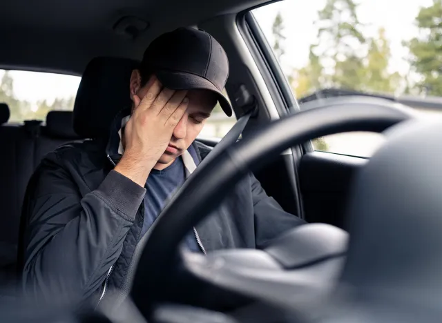 Tired man in car. Sleepy drowsy driver, fatigue. Driving and sleeping in vehicle. Exhausted, bored or drunk person. Serious upset man with stress, despair, anxiety or melancholy. Problem in traffic.