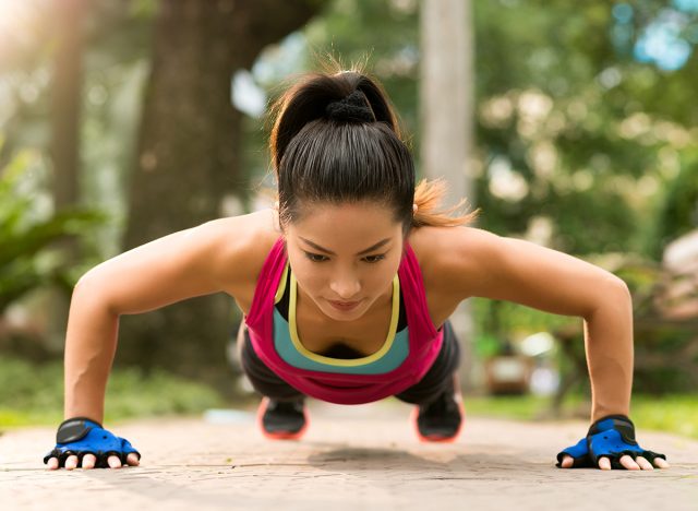 Sporty Asian woman doing push-ups outdoors