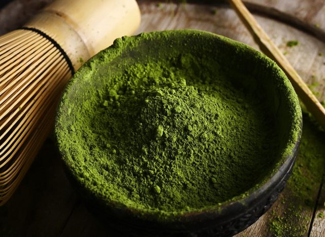 Matcha green tea powder in a bowl with a whisk for whipping and tea bamboo spoon