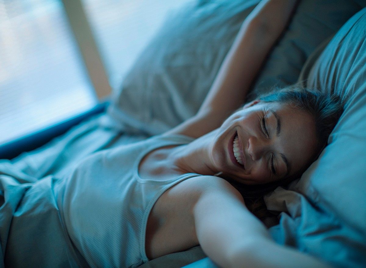 Young woman waking up in the morning in the bed in the bedroom