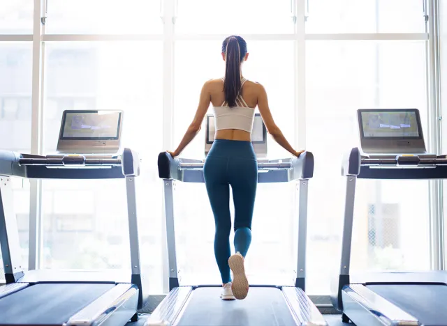 Rear view of young woman walking on treadmill