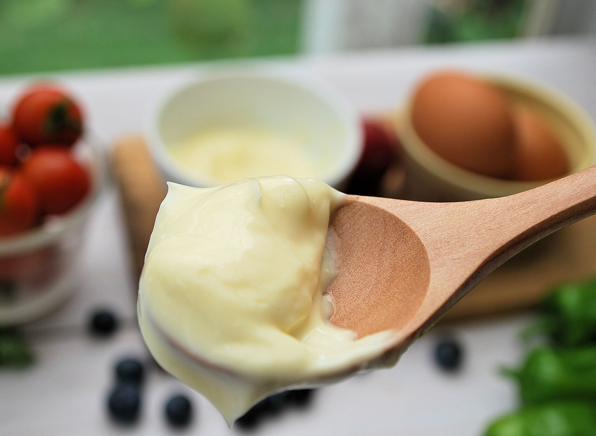 Close-up of mayonnaise on a spoon on a bright table.