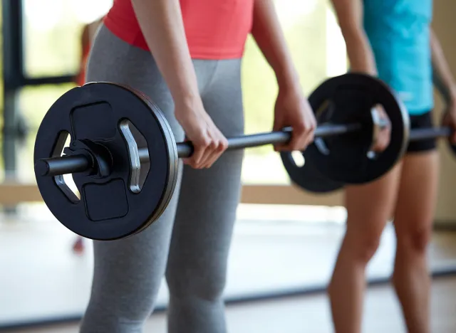 fitness, sport, training, people and lifestyle concept - group of women with barbells flexing muscles in gym