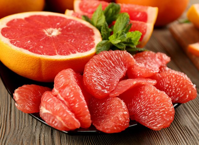 Juicy grapefruit pieces with fresh mint in a bowl, close up