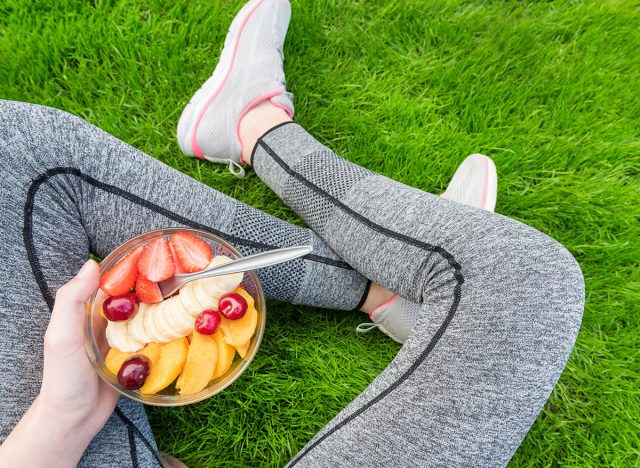 Young girl eating a fruit salad after a workout . Fitness and healthy lifestyle concept.