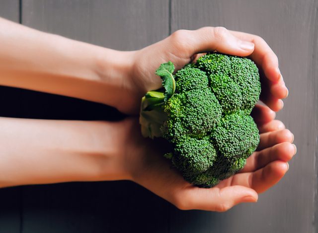 broccoli in hands. a wooden background. healthy eating concept.