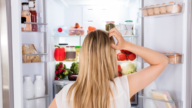 Rear View Of Young Woman Looking In Fridge At Kitchen