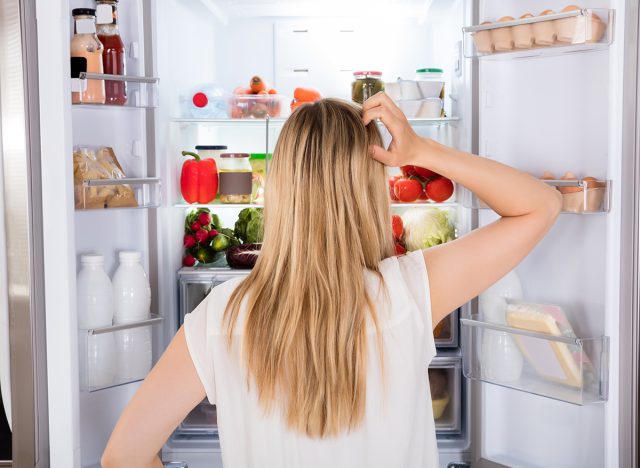 Rear View Of Young Woman Looking In Fridge At Kitchen