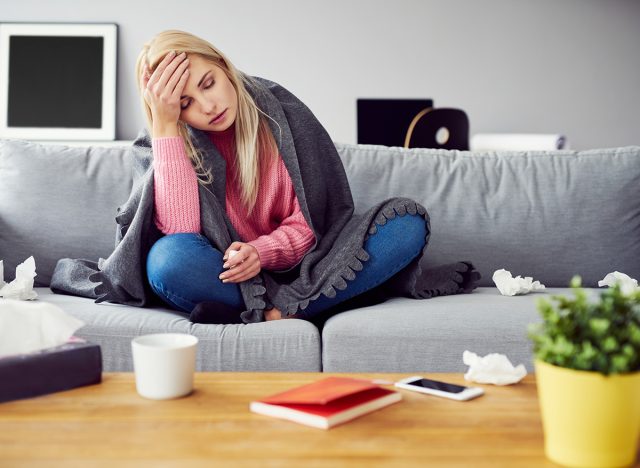 Sick woman with headache sitting under the blanket