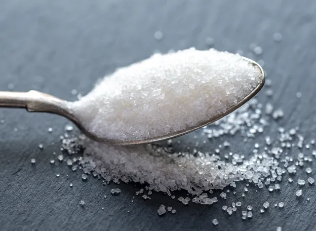 Spoon with white sugar on the dark background