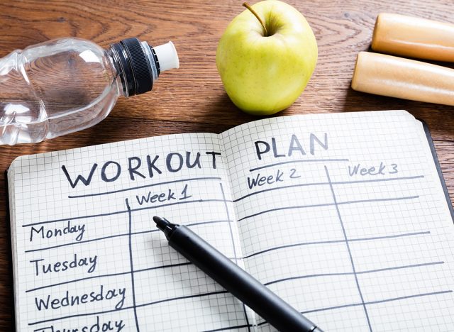 High Angle View Of A Workout Plan In Notebook At Wooden Desk