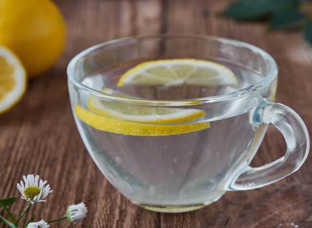 Delicious tea with lemon on a wooden background. A slice of lemon on the table. Water with lemon