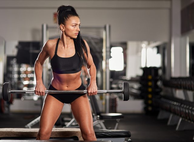 Athletic woman doing barbell rows in the gym