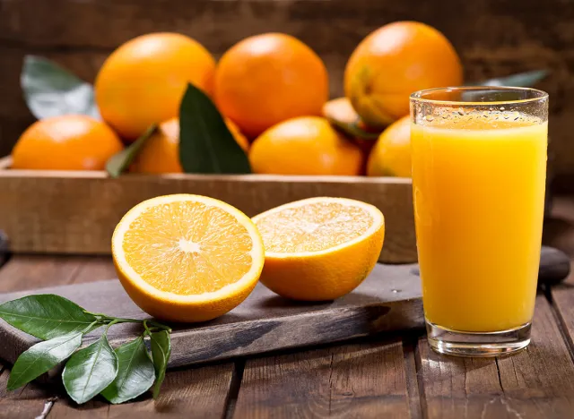 glass of fresh orange juice with fresh fruits on wooden table