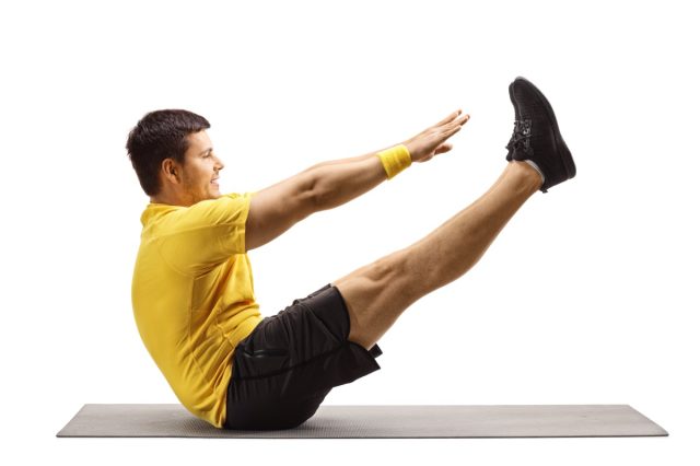 Full length profile shot of a young man stretching on an exercise mat isolated on white background