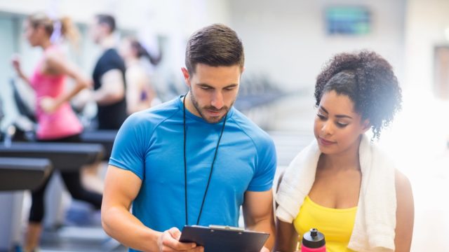 Fit woman talking to her trainer at the gym.