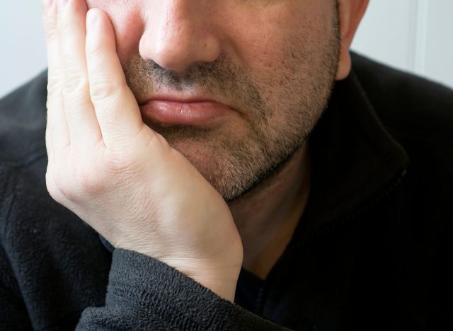 Close up man mouth with dry lips and unhappy face, Closeup shot of bearded half men face with chin on his hand with sad face.