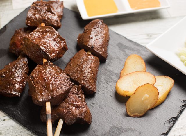 Traditional Peruvian food called anticuchos grilled skewered beef heart meat with boiled potato and white corn