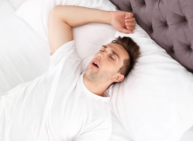 Young man sleeping in bed at home, top view