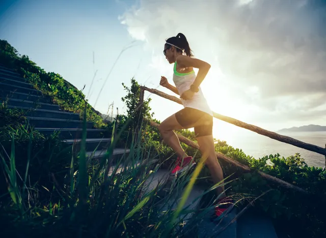 Determined woman running up on seaside mountain stairs