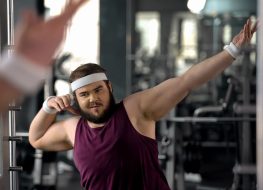 Trendy fat man showing dab move at mirror, satisfied with weight loss results
