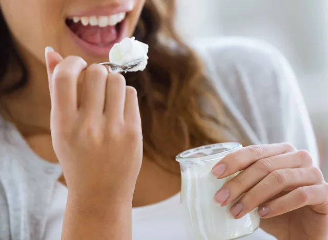 Close-up of woman's hand holding yogurt while eating at home.