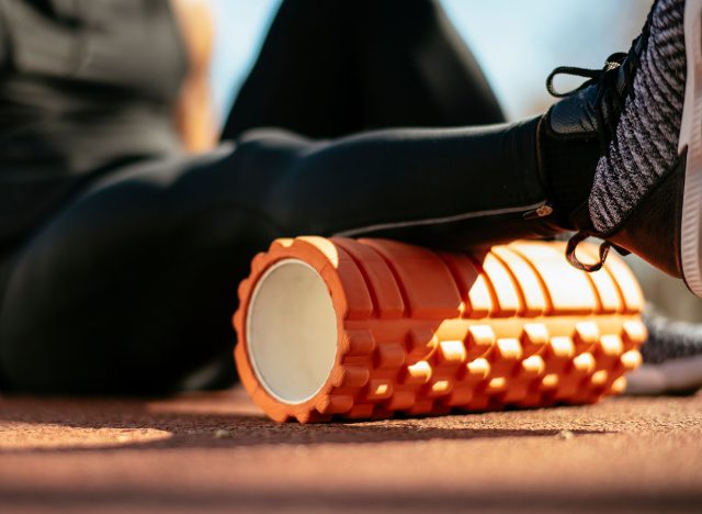 Man foam rolling. Athlete stretches using foam roller.