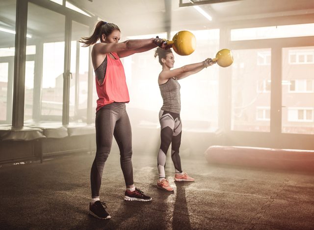 Two woman lifting kettle bell in cross fit gym