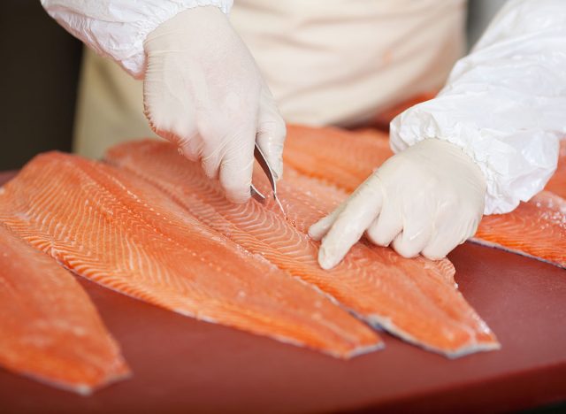workerÃ?Â´s hand deboning salmon at fish market