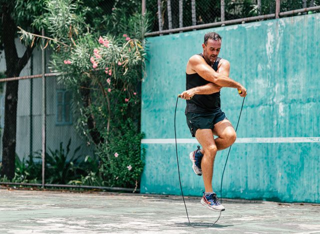 Full-length portrait of middle aged sportsman having training and doing rope jumping outdoors. Sport, fitness, street workout concept. Horizontal shot