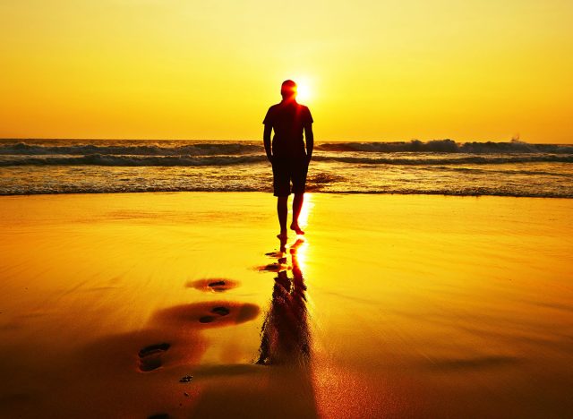 Silhouette of young man on the beach at sunset.