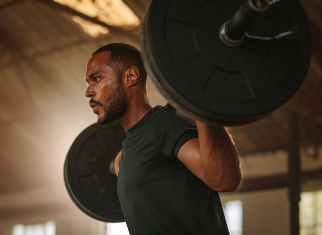 Man exercising with barbell. Male bodybuilder doing weight lifting workout at gym.