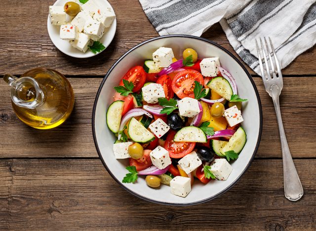 Classic Greek salad with fresh vegetables, feta cheese and olives. Healthy food. Wooden background. Top view