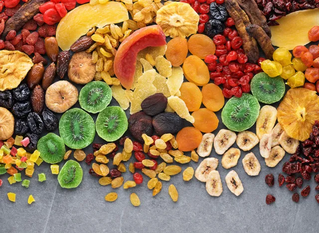 Dried fruits and berries on gray background top view. Lemons, oranges, bananas, raisins, cranberries, kiwi, cherries, ginger, plums, strawberries, dried apricots, tangerines, dates, pineapples, figs,