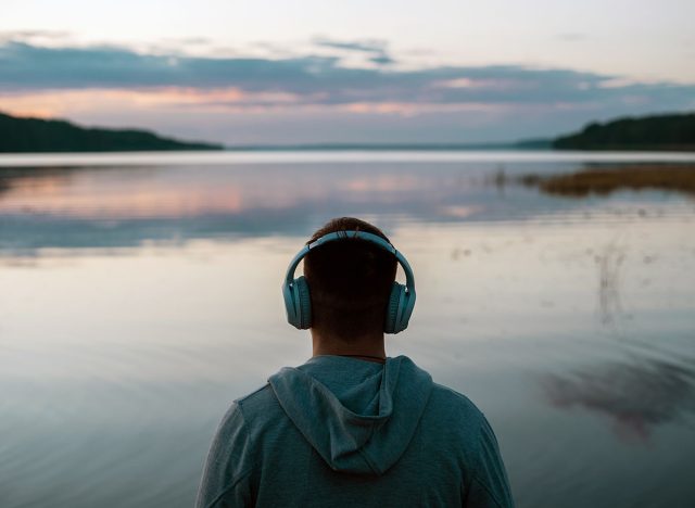 A man meditates with headphones in nature. He listens to pleasant, calm music before going to bed. Balance calmness and harmony with yourself.