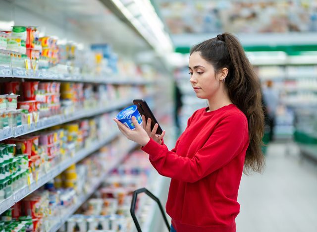 Shopping. A young pretty woman scans the qr code on a product using cellphone. Indoor. Concept of modern technologies and shopping.