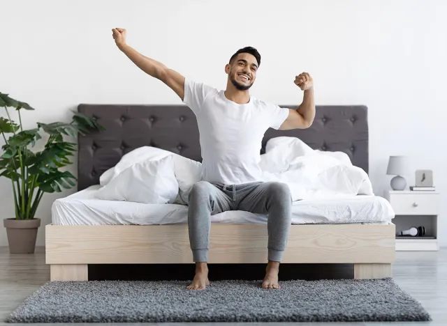 Handsome Happy Young Arab Guy Waking Up In The Morning, Sitting On Bed And Stretching After Good Sleep, Smiling Millennial Middle Eastern Man Having Good Mood, Enjoying Start Of New Day, Copy Space