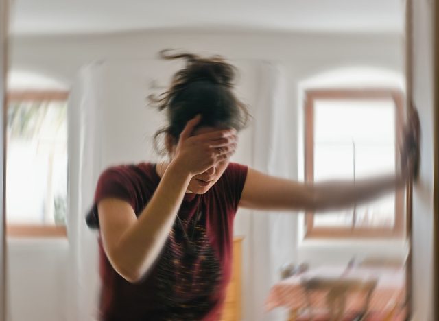 Blured photo of a woman suffering from vertigo or dizziness or other health problem of brain or inner ear.