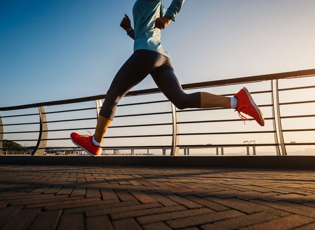 Fitness woman runner running on seaside bridge