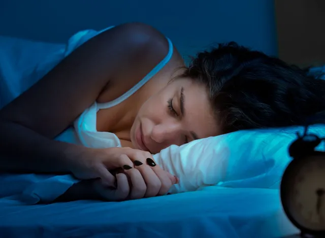 Woman sleeping in a bed in a dark bedroom