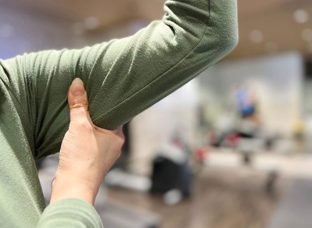 A woman rubbing her upper arm at the fitness gym