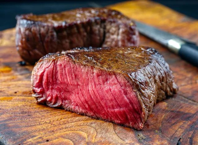 Traditional fried dry aged bison beef rump steak served as close-up in a rustic old wooden board