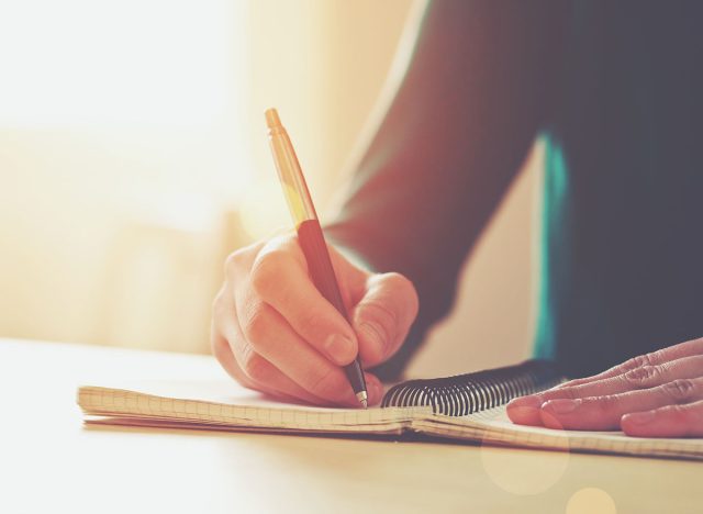 female hands with pen writing on notebook