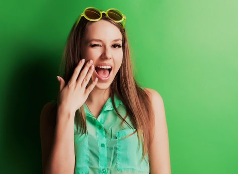 Portrait of a cheerful young girl in bright casual clothes smiling at the camera with beautiful smile. Colorful background